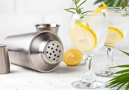 Glas gin en tonic met een cocktailshaker op een tafel