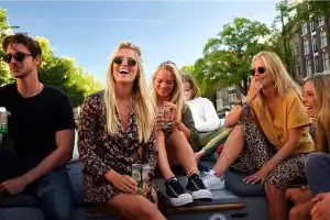 Groep genietend van Amsterdam met een drankje op Sloep Vibe