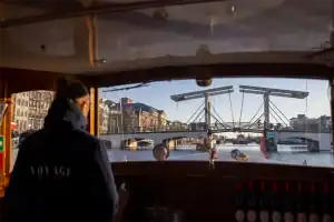 Schipper varend op de Saloonsloep met uitzicht op Amsterdamse brug