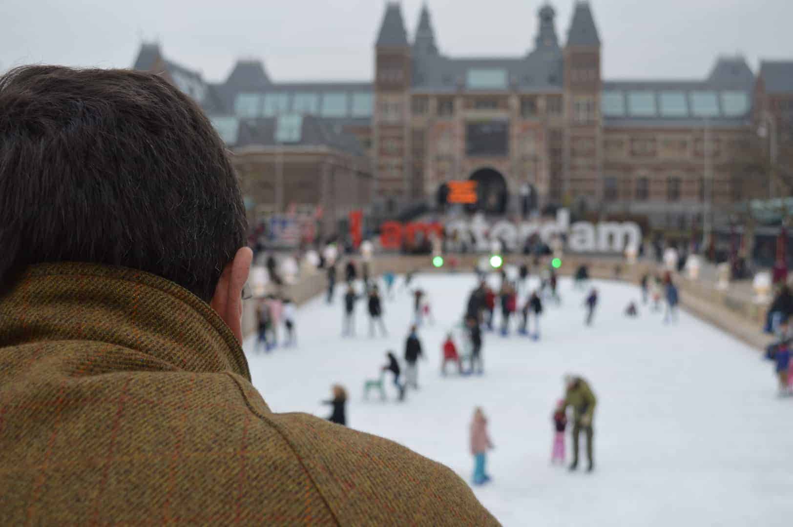 Mann beobachtet Schlittschuhläufer auf dem Museumplein in Amsterdam